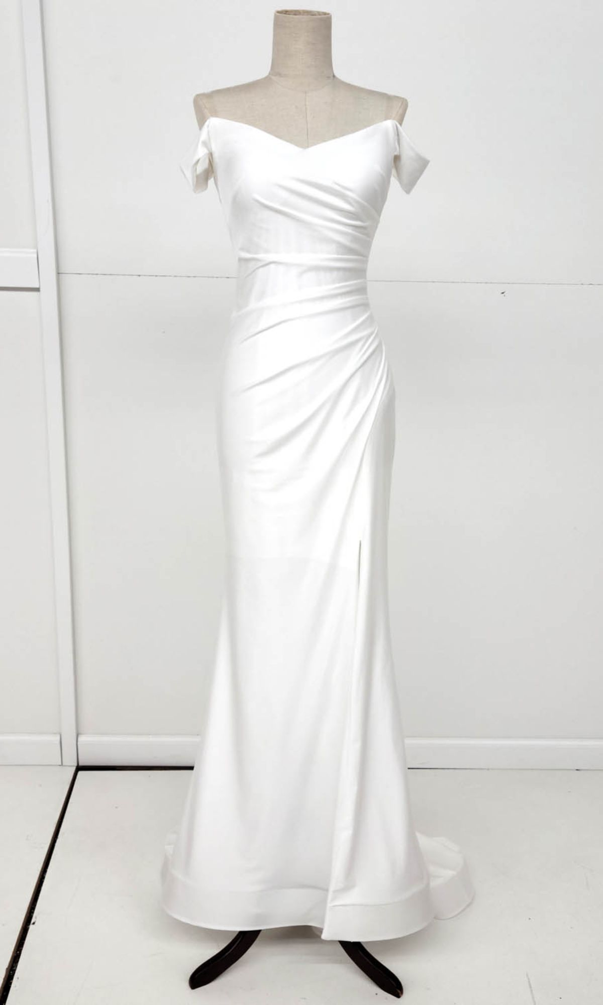 The Off-the-Shoulder Long Prom Dress: Chicas YG5025 is a white, floor-length gown with a fitted bodice and draped detailing, shown on a mannequin against a plain background.